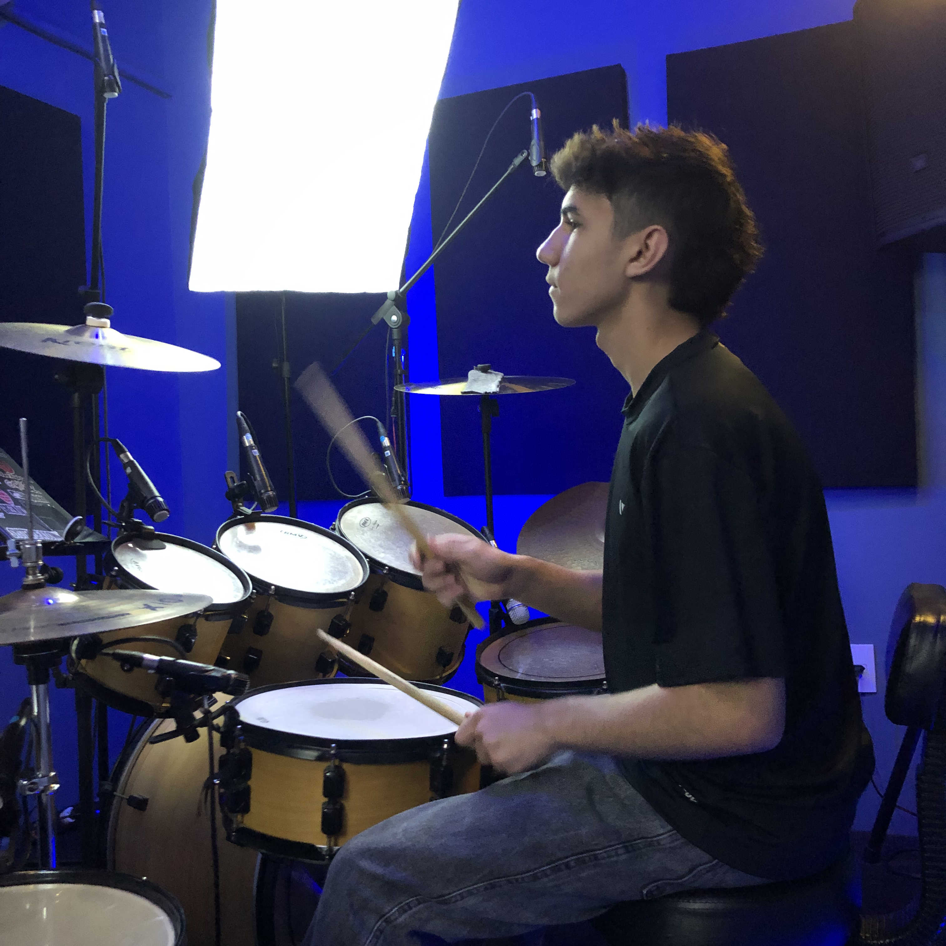 Aluno durante aula de bateria em Londrina com pedal duplo e bateria completa.